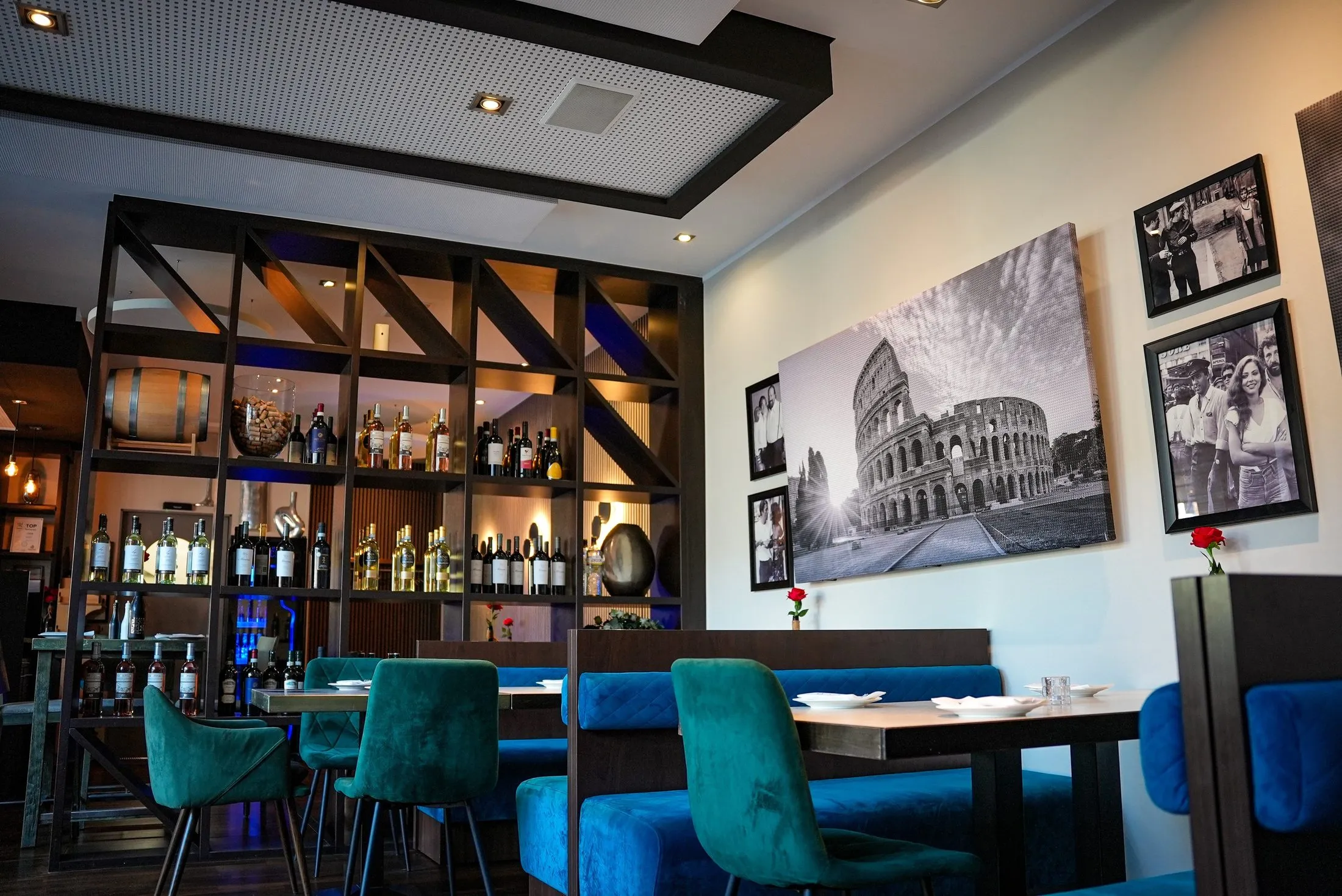 Gastraum mit Weinregal, Samtstühlen und Kolosseum Bild im Ristorante La Rosa Stadtlohn